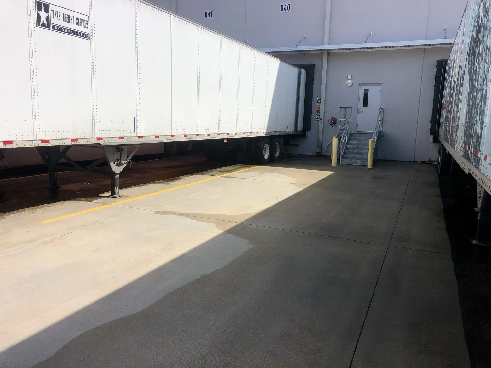 Concrete loading dock lane after pressure washing, showing the cleaned surface beside trailers